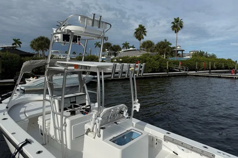 Slide: The Image of 2023 T Craft 27 boat docked by palm trees under cloudy sky. - 6