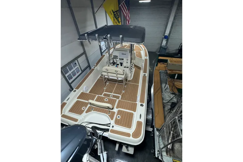 Slide: The Image of 2011 Hydra-Sports Bay Bolt 23 boat in a garage, featuring a spacious deck and T-top. - 10