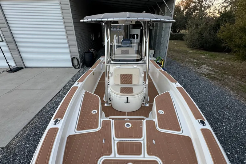Slide: The Image of 2011 Hydra-Sports Bay Bolt 23 boat with tan deck, parked near a garage. - 12