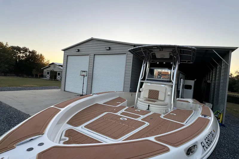 Slide: The Image of 2011 Hydra-Sports Bay Bolt 23 boat parked near a large garage at sunset. - 16
