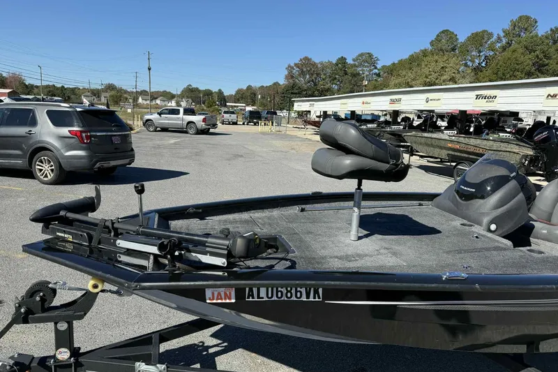Slide: The Image of 2021 Bass Tracker 190 PT boat in parking lot with vehicles and dealership in background. - 2
