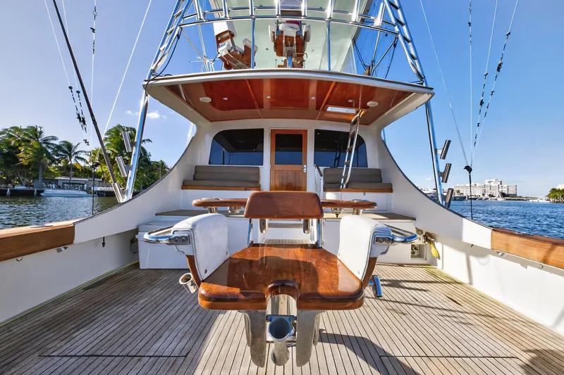 Slide: The Image of 2004 B&D 65 Flybridge yacht deck with fishing chair, docked by palm trees. - 12