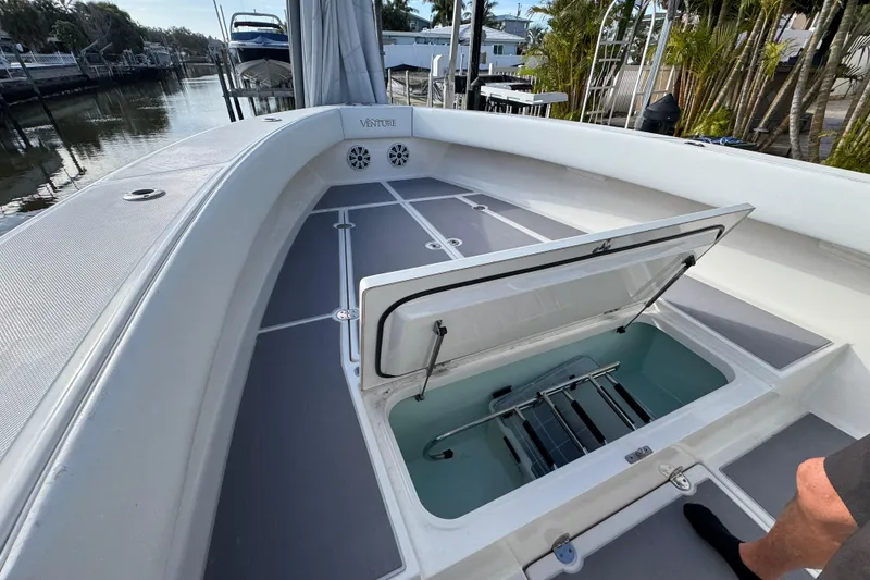 Slide: The Image of 2009 Venture 39 Center Console boat with open storage compartment, docked near palm trees. - 28