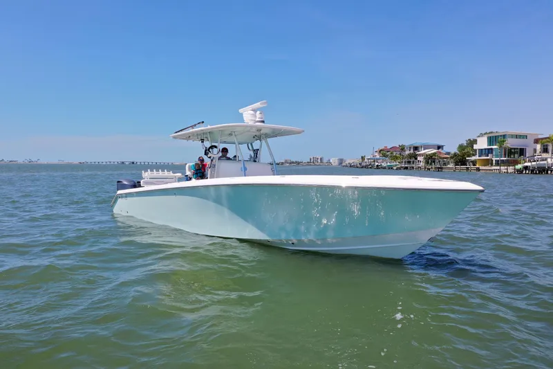 Slide: The Image of 2009 Venture 39 Center Console boat cruising on a sunny day near coastal homes. - 33