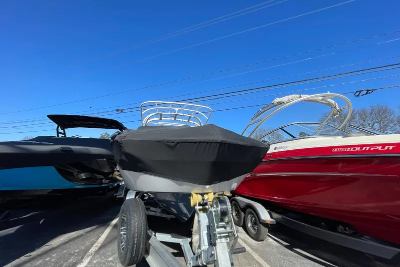 Slide: The Image of 2019 Yamaha Boats 242 Limited S E-Series covered on trailer, parked beside red boat. - 9