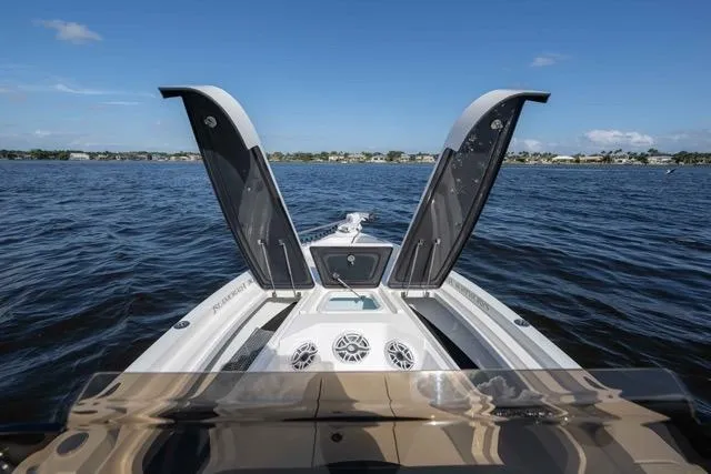 Slide: The Image of 2024 Islamorada Boatworks 24 on water, open storage compartments, clear sky, and distant shoreline. - 10