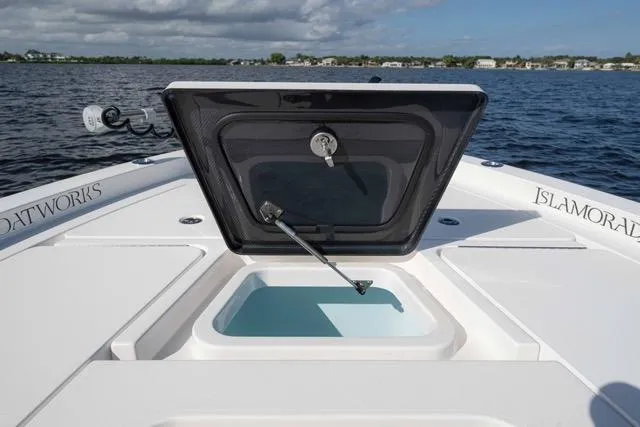 Slide: The Image of 2024 Islamorada Boatworks 24 with open hatch, on calm water, showcasing storage compartment. - 5