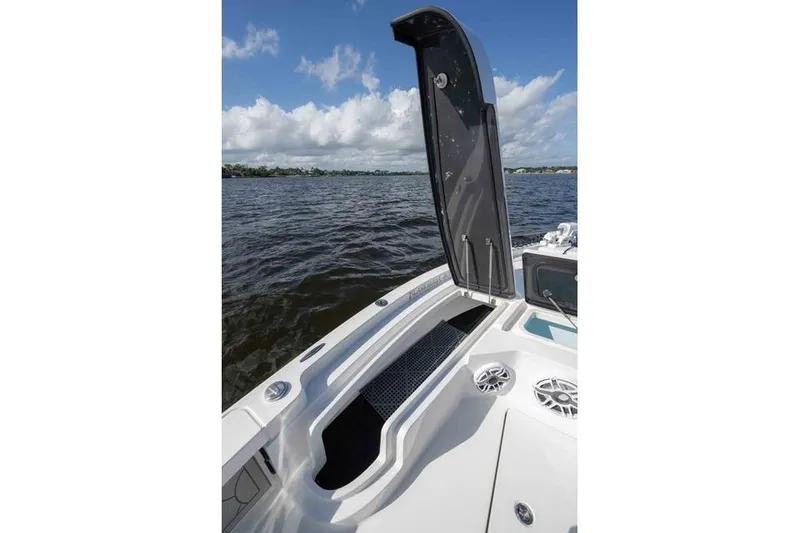 Slide: The Image of 2024 Islamorada Boatworks 24, open storage compartment, on calm water under blue sky. - 6