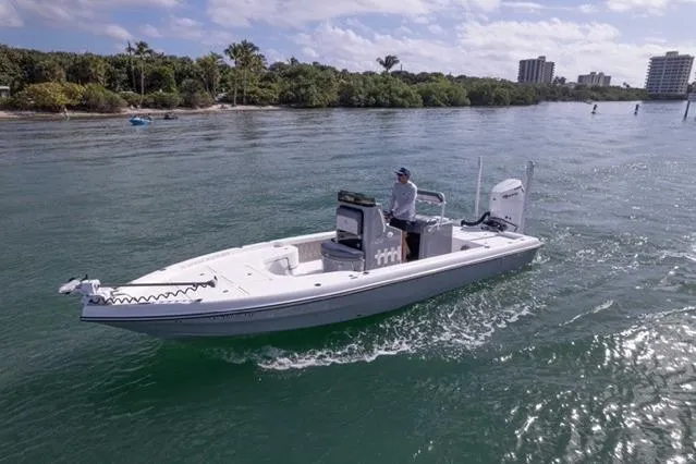 Slide: The Image of 2024 Islamorada Boatworks 24 cruising on a scenic waterway with lush greenery and buildings. - 62