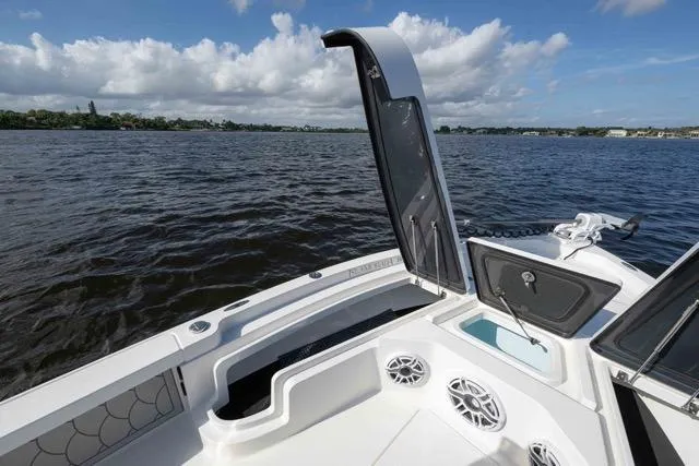 Slide: The Image of 2024 Islamorada Boatworks 24, open hatch, speakers, and water view under a cloudy sky. - 8