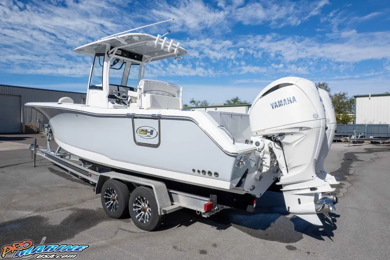 Slide: The Image of 2024 Sea Hunt Gamefish 27 boat with Yamaha engine on trailer, under clear blue sky. - 12