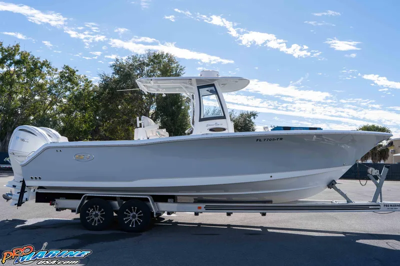 Slide: The Image of 2024 Sea Hunt Gamefish 27 boat on trailer, side view under clear sky. - 27