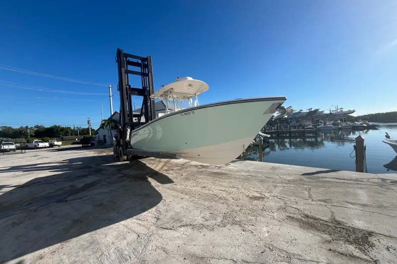 Slide: The Image of 2017 Cobia 277 Center Console boat lifted by forklift near marina. - 1