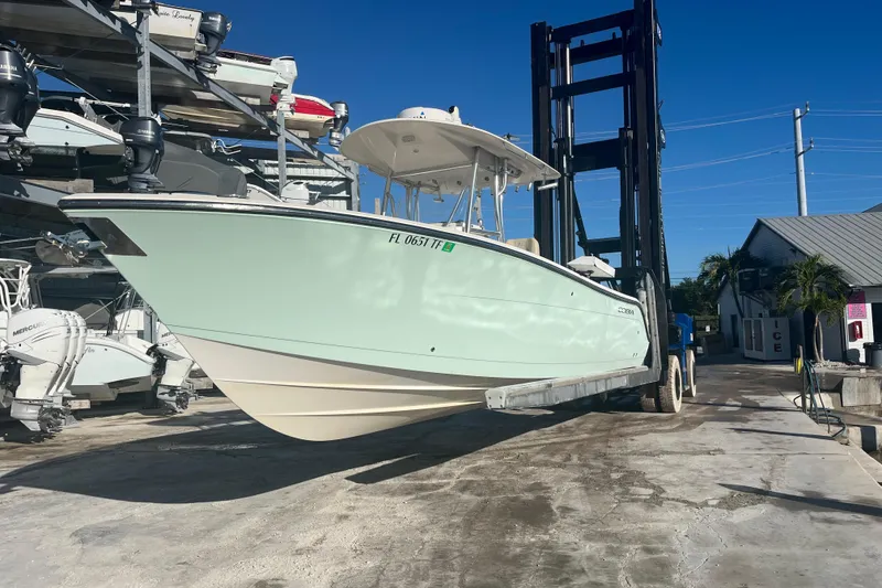 Slide: The Image of 2017 Cobia 277 Center Console boat on forklift at marina, clear blue sky. - 2