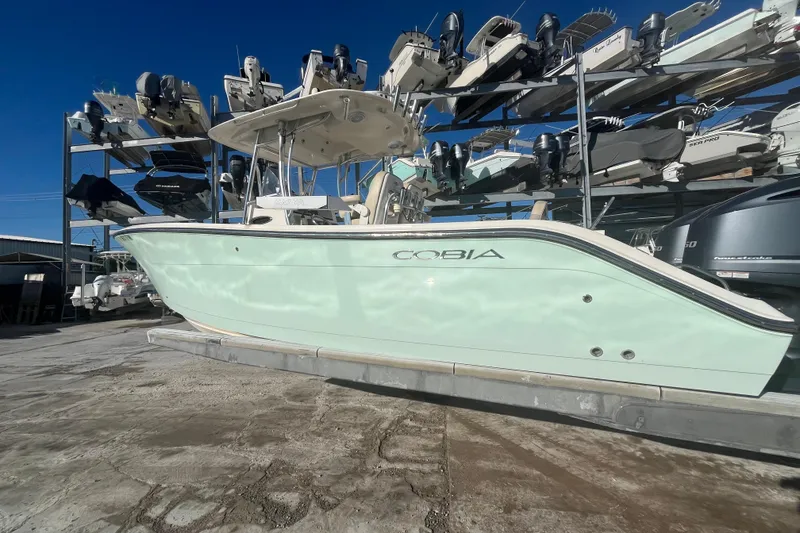 Slide: The Image of 2017 Cobia 277 Center Console boat in storage, surrounded by other vessels. - 3