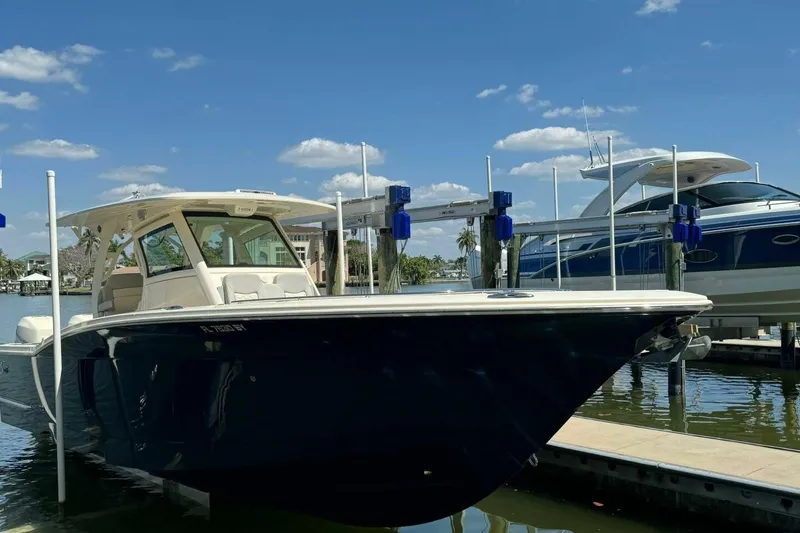 Slide: The Image of 2021 Scout 330 LXF boat docked at marina under clear blue sky. - 2
