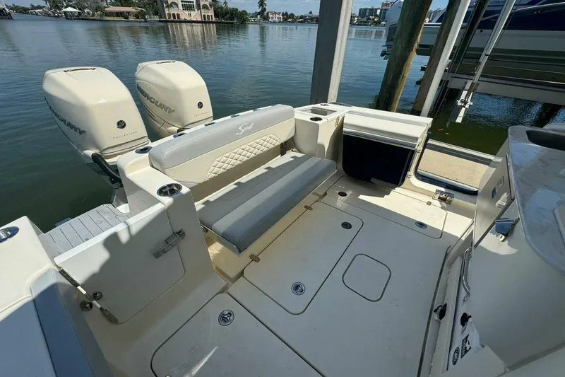 Slide: The Image of 2021 Scout 330 LXF boat interior with twin Mercury engines, docked by the water. - 6