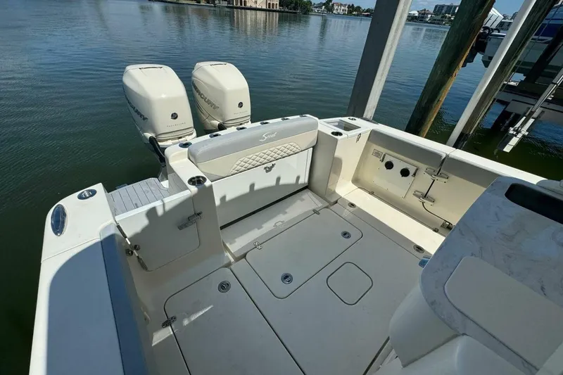 Slide: The Image of 2021 Scout 330 LXF boat with twin Mercury engines, docked on calm water. - 7