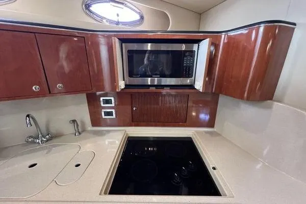 Slide: The Image of 2003 Sea Ray 410 Sundancer kitchen with microwave, stove, and wooden cabinets. - 18