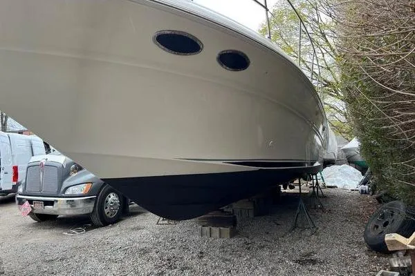 Slide: The Image of 2003 Sea Ray 410 Sundancer yacht on stands, parked near vehicles and trees. - 37