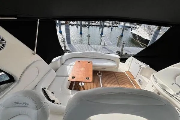 Slide: The Image of 2003 Sea Ray 410 Sundancer yacht interior with seating and wooden table, docked at marina. - 9