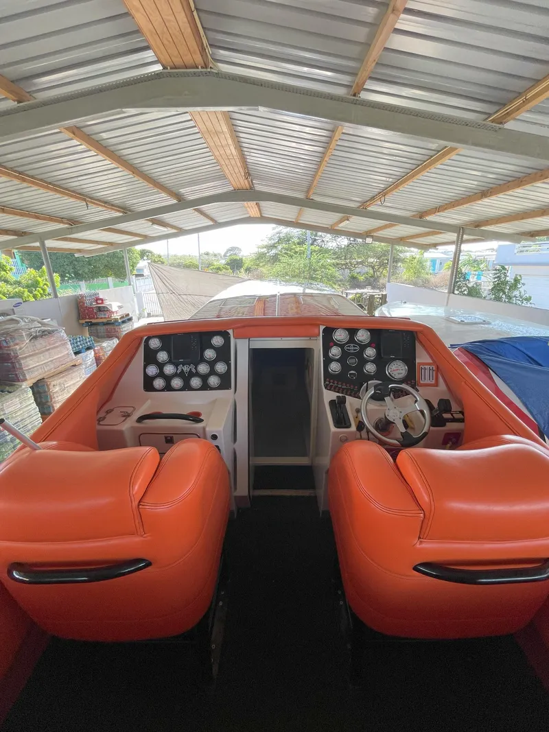 Slide: The Image of 2002 Cigarette ROUGH RIDER boat cockpit with orange seats under a metal roof. - 10