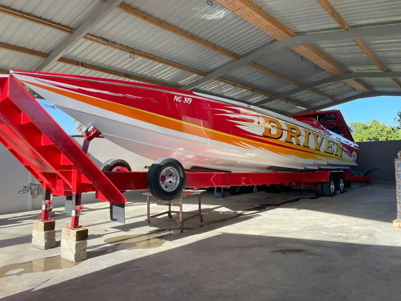Slide: The Image of 2002 Cigarette ROUGH RIDER boat in a garage, red and white design, on a trailer. - 18