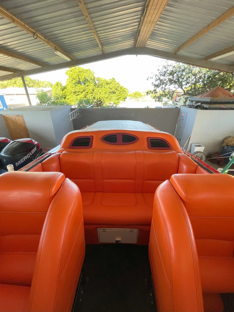 Slide: The Image of 2002 Cigarette ROUGH RIDER boat with vibrant orange seating under a metal roof. - 22