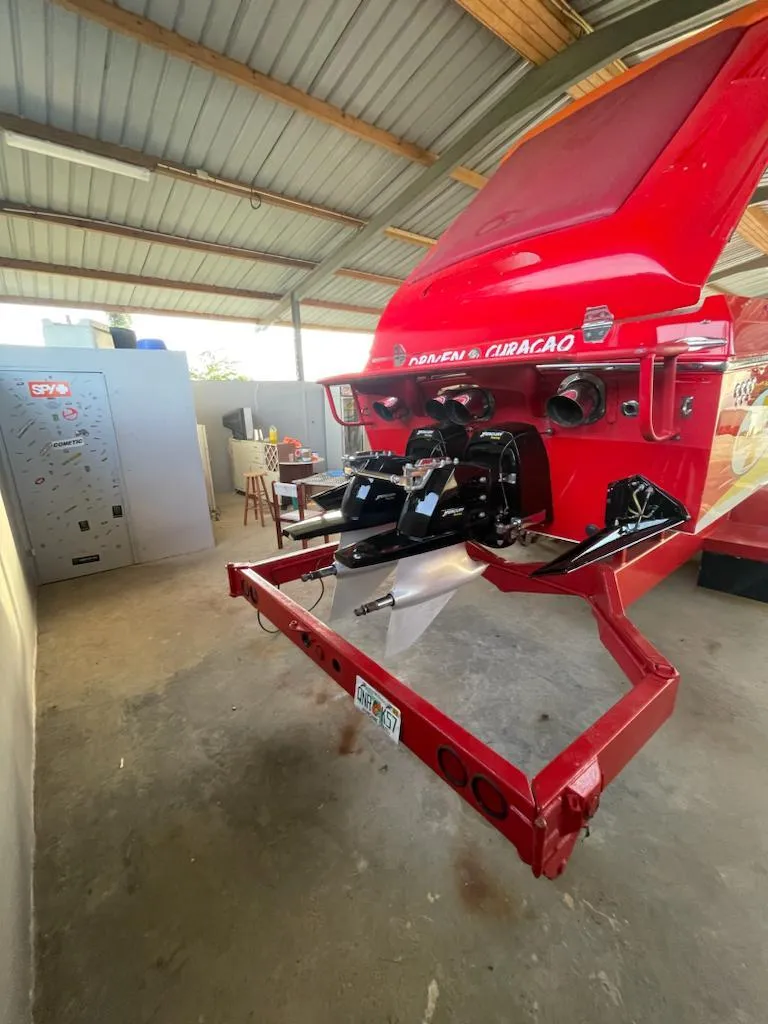 Slide: The Image of Red 2002 Cigarette ROUGH RIDER boat in a garage, showcasing its powerful engine. - 4