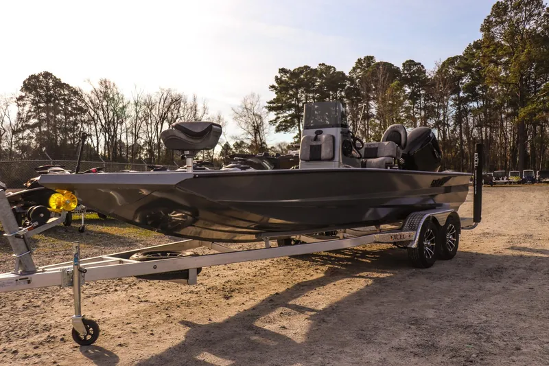 Slide: The Image of 2026 Excel 220 Bay Pro Elite boat on trailer, parked outdoors, surrounded by trees. - 6