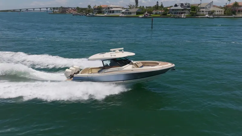 Slide: The Image of 2022 Chris-Craft Calypso 35 cruising on blue water near coastal homes. - 12