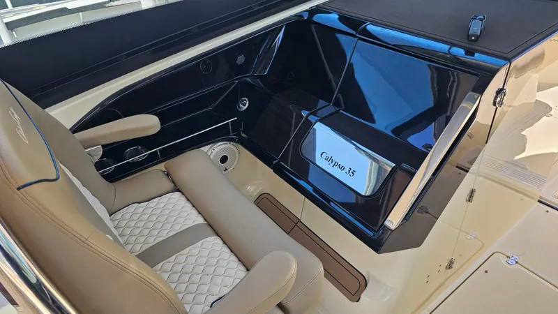 Slide: The Image of 2022 Chris-Craft Calypso 35 interior with beige seating and sleek black dashboard. - 18