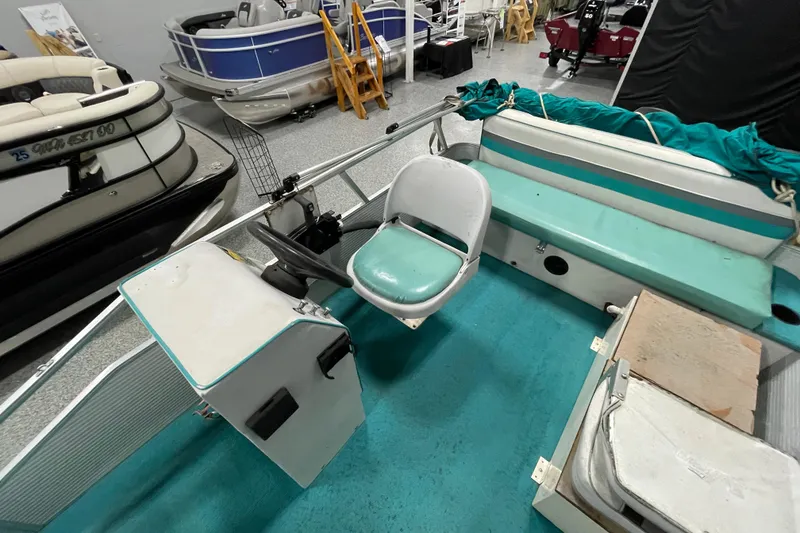 Slide: The Image of 1995 Weeres Fish 16 pontoon boat interior with teal seating and steering console. - 8