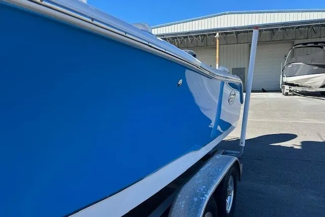 Slide: The Image of 2020 Sea Hunt Ultra 225 boat on trailer, blue hull, parked near a warehouse. - 9