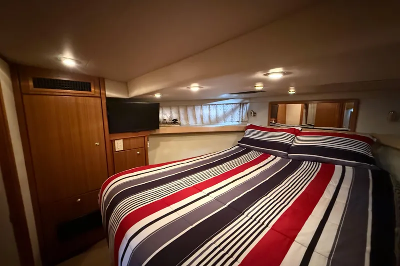 Slide: The Image of Cozy bedroom in 2002 Bayliner 4788 Pilot House Motoryacht with striped bedding and TV. - 20