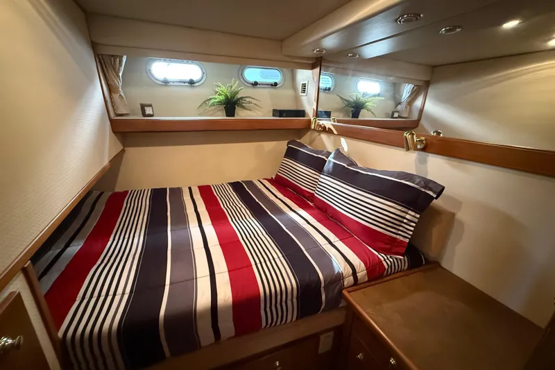 Slide: The Image of Cozy bedroom in 2002 Bayliner 4788 Pilot House Motoryacht with striped bedding and porthole windows. - 24