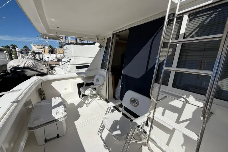 Slide: The Image of 2002 Bayliner 4788 Pilot House Motoryacht deck with chairs and ladder, docked at marina. - 3