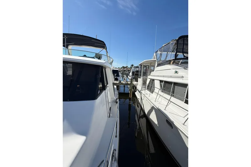 Slide: The Image of 2002 Bayliner 4788 Pilot House Motoryacht docked alongside other boats under clear blue sky. - 30
