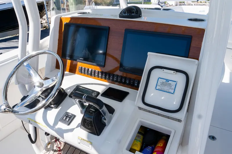 Slide: The Image of 2013 Jupiter 34 FS boat dashboard with steering wheel, controls, and navigation screens. - 16