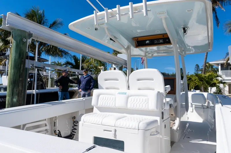 Slide: The Image of 2013 Jupiter 34 FS boat with white seating and T-top, docked under clear blue sky. - 23