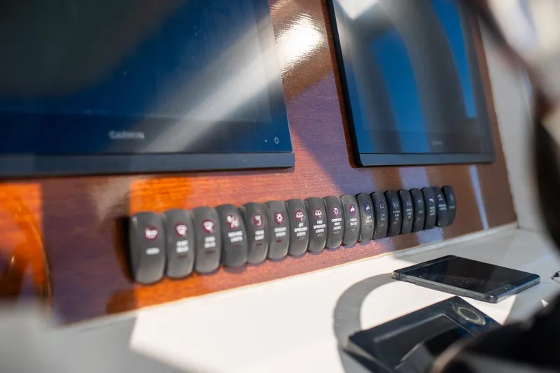 Slide: The Image of Control panel of 2013 Jupiter 34 FS boat with multiple switches and screens. - 47