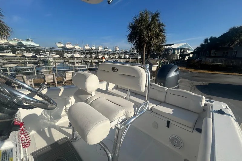 Slide: The Image of 2019 Sea Hunt Ultra 211 boat interior at marina with palm trees and docked boats. - 11