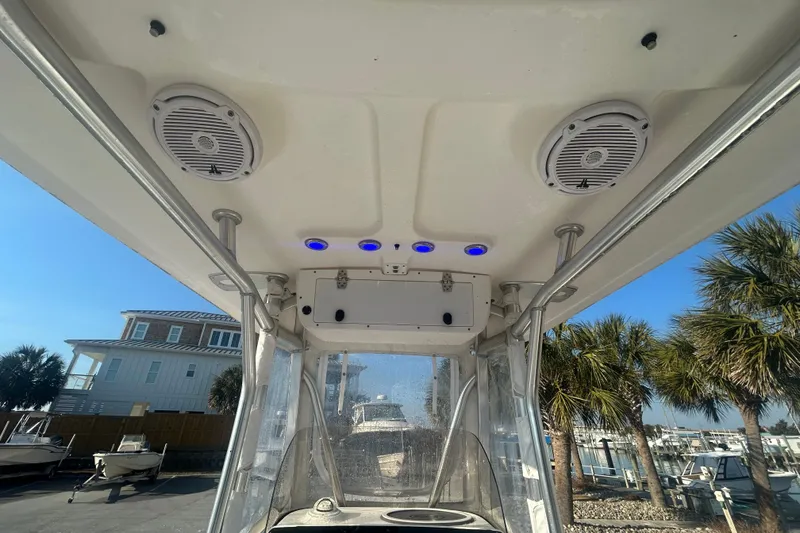 Slide: The Image of 2019 Sea Hunt Ultra 211 boat interior with speakers and blue lights, docked near palm trees. - 17