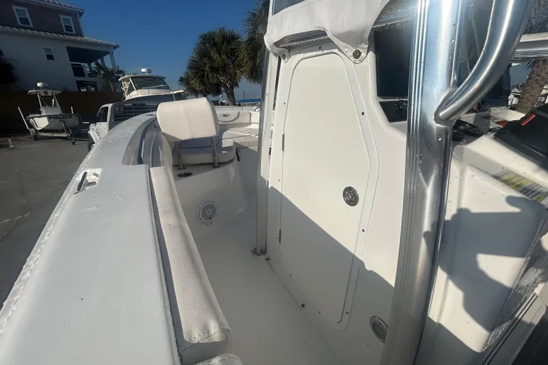 Slide: The Image of 2019 Sea Hunt Ultra 211 boat interior with seating and console, docked near palm trees. - 20