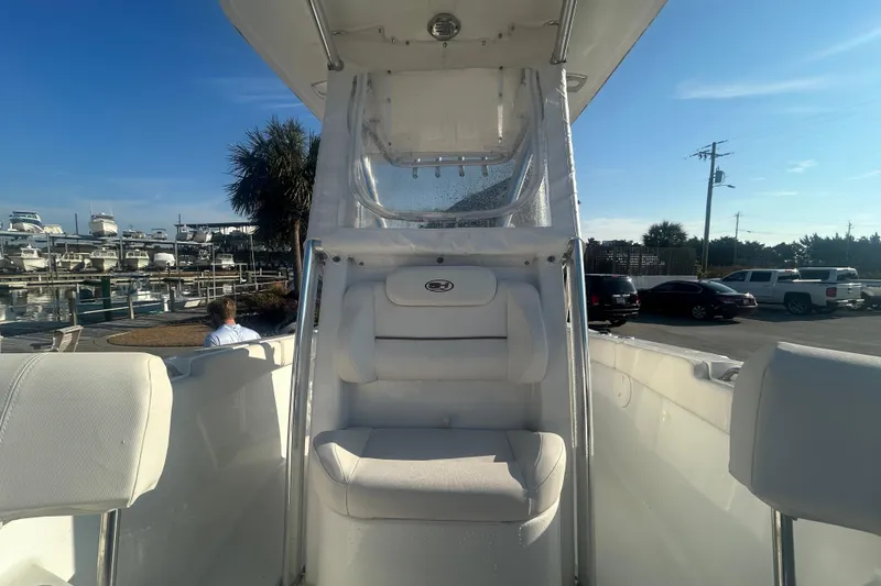 Slide: The Image of 2019 Sea Hunt Ultra 211 boat interior with seating, docked at marina under clear blue sky. - 23