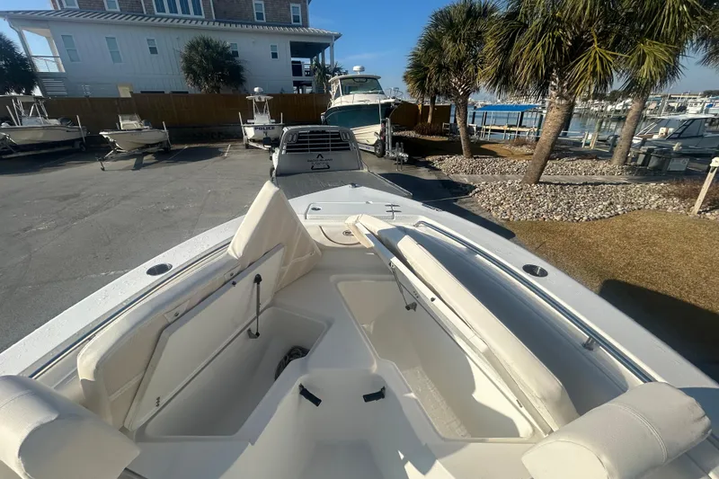 Slide: The Image of 2019 Sea Hunt Ultra 211 boat interior with seating, docked near palm trees and waterfront. - 25