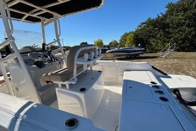 Slide: The Image of 2026 Bayliner Trophy T20CC boat interior with seating and console, parked outdoors. - 11
