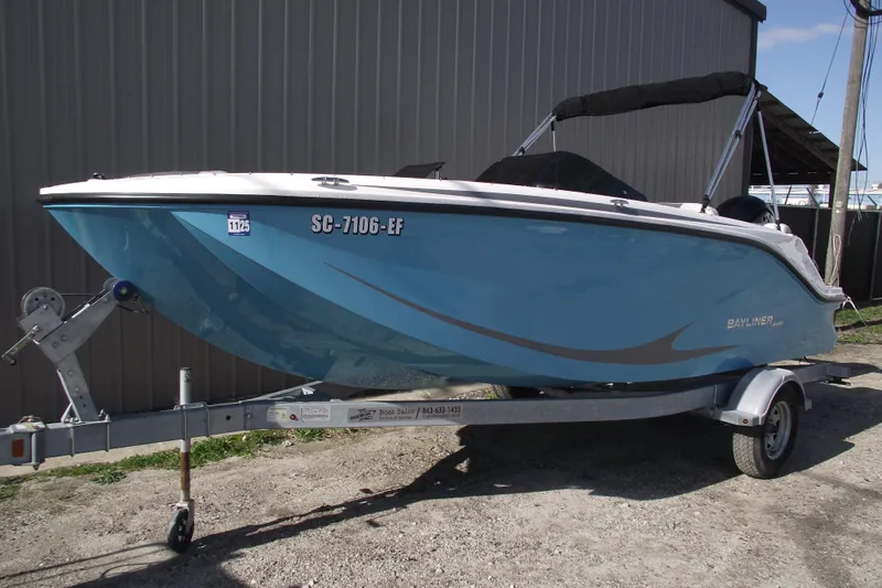 Slide: The Image of 2024 Bayliner Element M19 boat on trailer, blue hull, parked outdoors. - 1