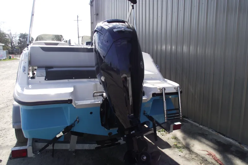 Slide: The Image of 2024 Bayliner Element M19 boat with outboard motor, parked near a metal building. - 3