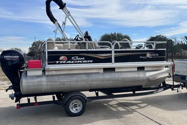 Slide: The Image of 2020 Sun Tracker Bass Buggy 16 DLX pontoon boat on trailer, featuring Mercury outboard motor. - 2